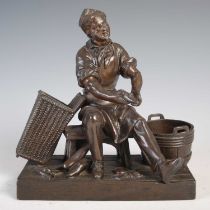 A bronzed spelter figure of a cobbler, 17cm wide x 18cm high.