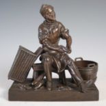 A bronzed spelter figure of a cobbler, 17cm wide x 18cm high.