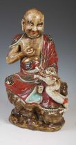 A Chinese porcelain figure of Lohan and dragon, late 19th / early 20th century, decorated with a