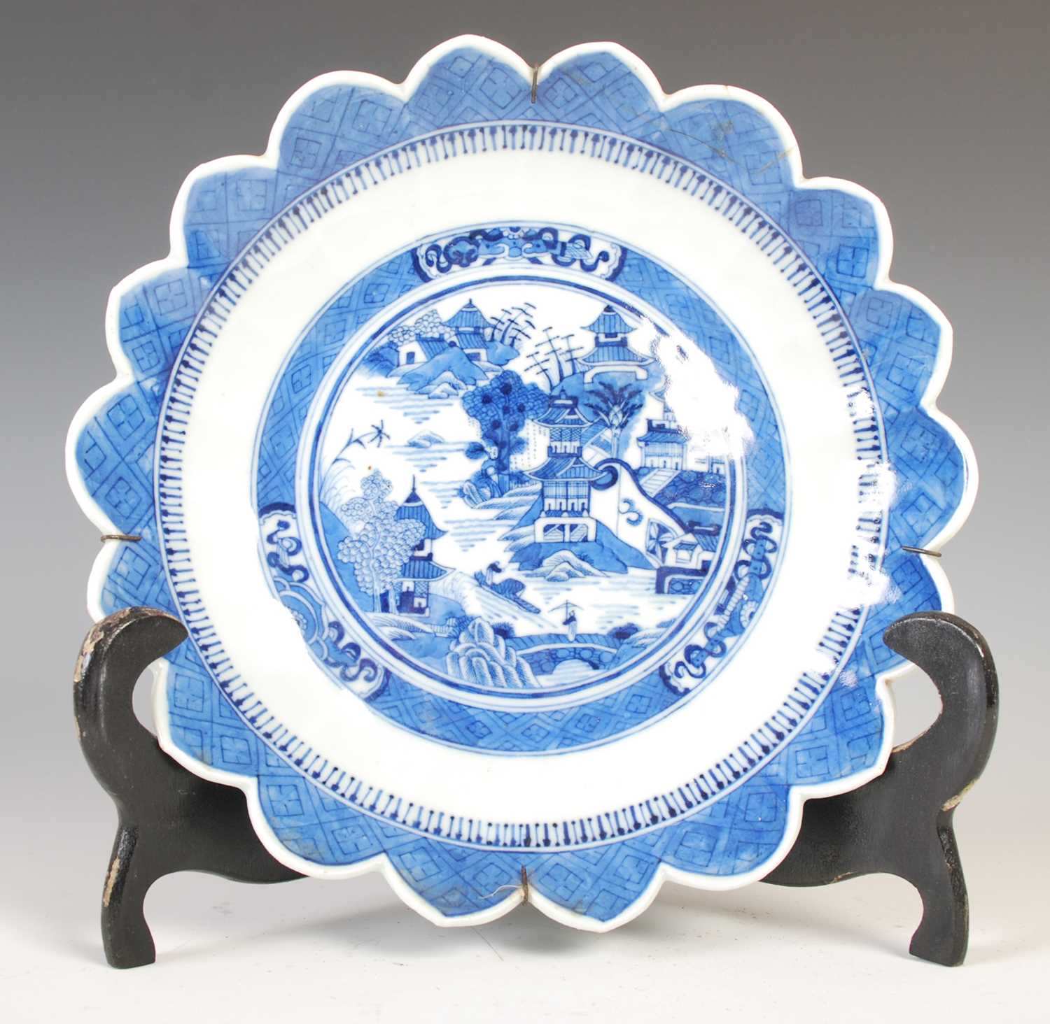A Chinese porcelain blue and white flower shaped dish, Qing Dynasty, decorated with pavilions in a