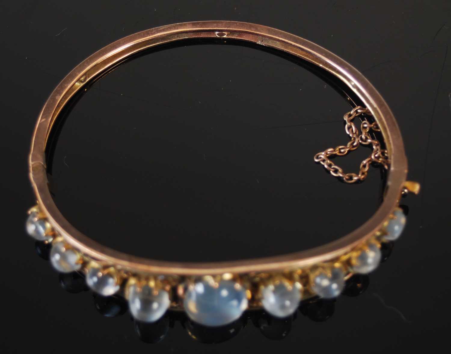 A yellow metal and moonstone hinged bangle, centred an oval cabochon cut moonstone flanked on either - Image 3 of 3