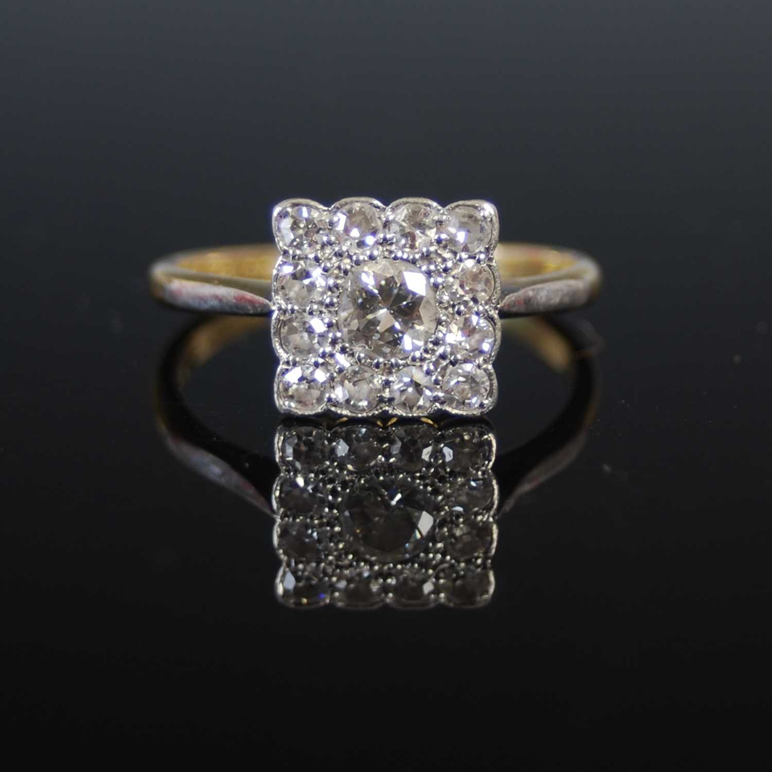 A yellow and white metal diamond cluster ring, set with a central round brilliant cut diamond in a