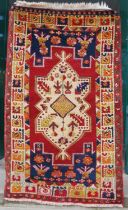 A Turkish rug, 20th century, the rectangular madder ground centred with a large ivory-coloured