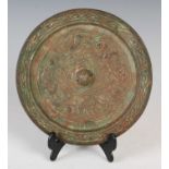 A Chinese bronze mirror, of circular form, cast in relief with four stylised animals, 19cm