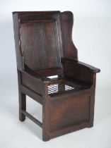 An early 18th century oak lambing chair, the rectangular panelled back flanked by shaped lugs over a