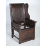 An early 18th century oak lambing chair, the rectangular panelled back flanked by shaped lugs over a