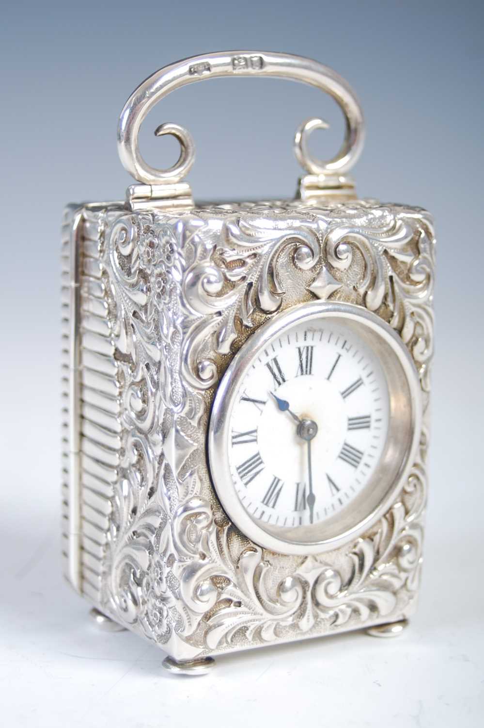 A late 19th century silver carriage clock, the white enamel dial with Roman numerals, in richly
