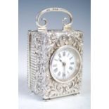 A late 19th century silver carriage clock, the white enamel dial with Roman numerals, in richly