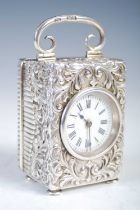 A late 19th century silver carriage clock, the white enamel dial with Roman numerals, in richly