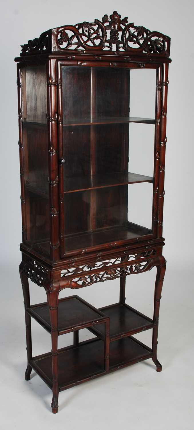 A Chinese dark wood display cabinet, late 19th/ early 20th century, the upper section with bamboo,