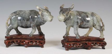 A pair of Chinese green stone models of Ox, early 20th century, carved standing, mounted on carved