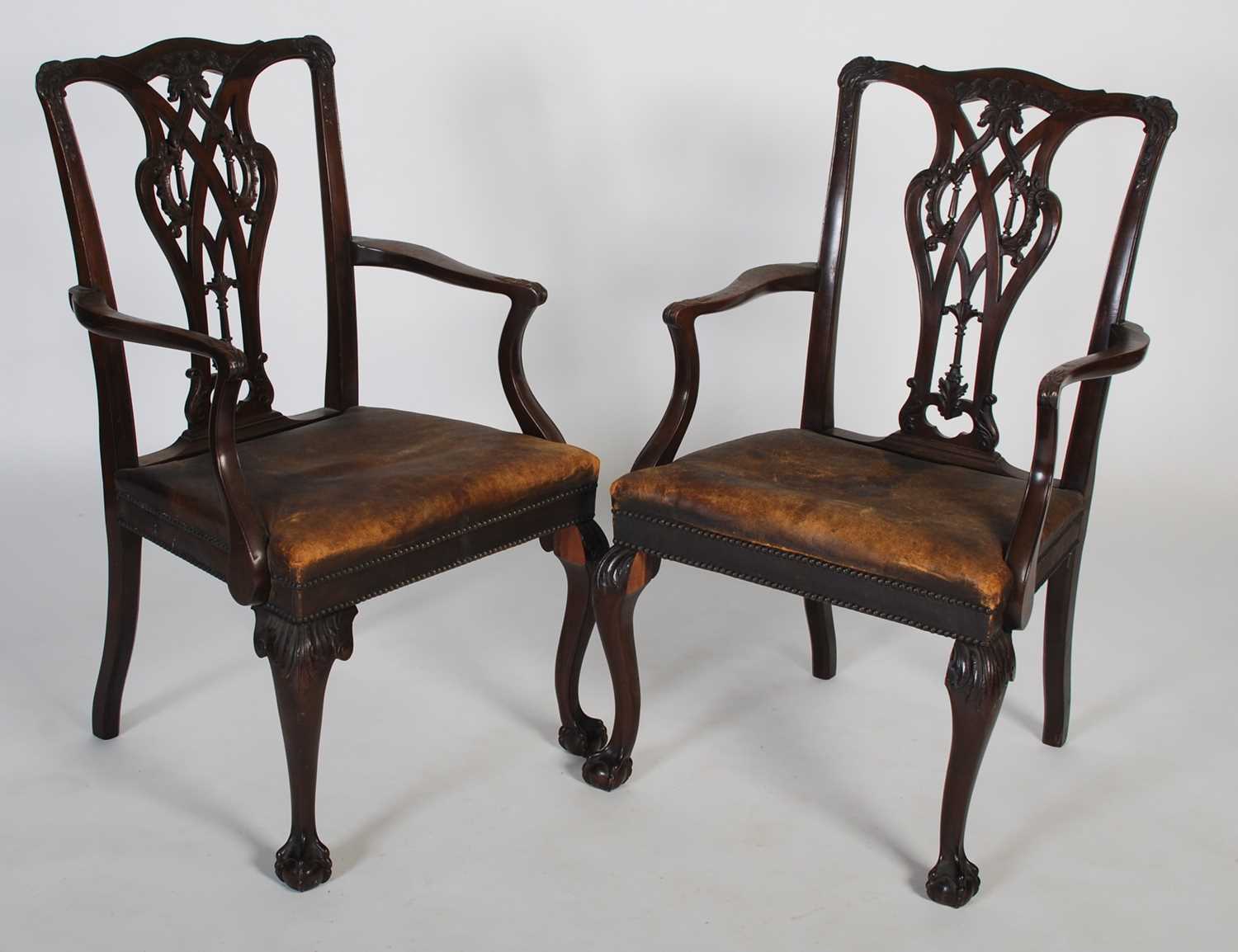 A pair of early 20th century George III style elbow chairs, the shaped top rail above a carved and
