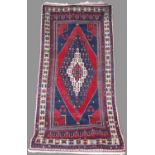 A Persian long rug, 20th century, the rectangular madder ground centred with a large lozenge