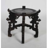 A Chinese ebonised urn stand, early 20th century, the dished circular top raised on four archaic