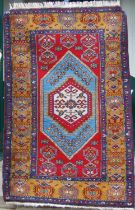 A Turkish rug, 20th century, the rectangular madder ground centred with a blue ground lozenge