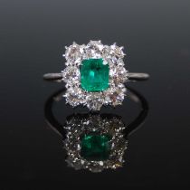An early 20th century white metal, emerald and diamond cluster ring, centred with an emerald cut