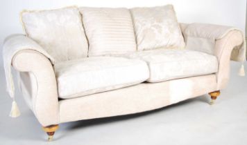 A modern Victorian style two-seat sofa, with loose cushion back and seat, raised on tapered turned