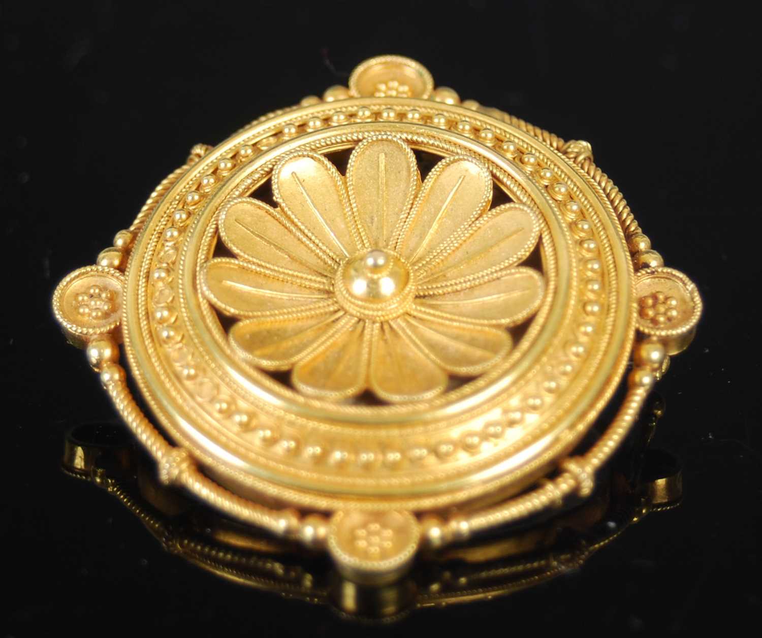 A late 19th century yellow metal locket brooch, centred with a stylised flower, the reverse with