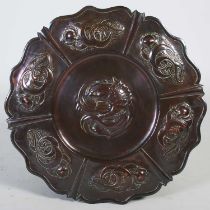 A large Arts & Crafts Newlin School patinated copper charger, of shaped circular form, richly