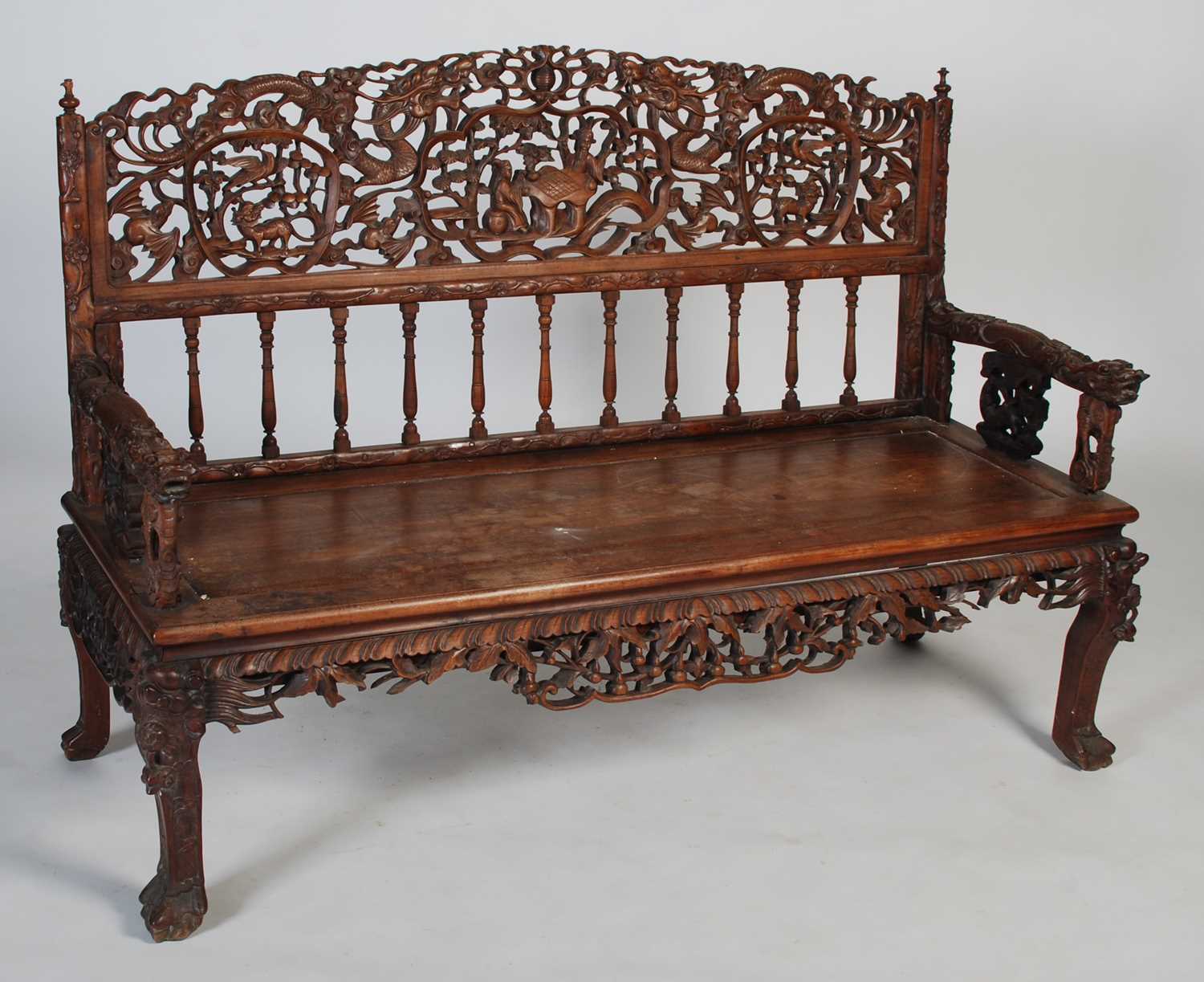 A Chinese dark wood bench, late 19th/ early 20th century, the rectangular back carved and pierced