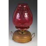 A late 19th century brass oil burning paraffin lamp, with ruby glass shade, 42.5cm high.