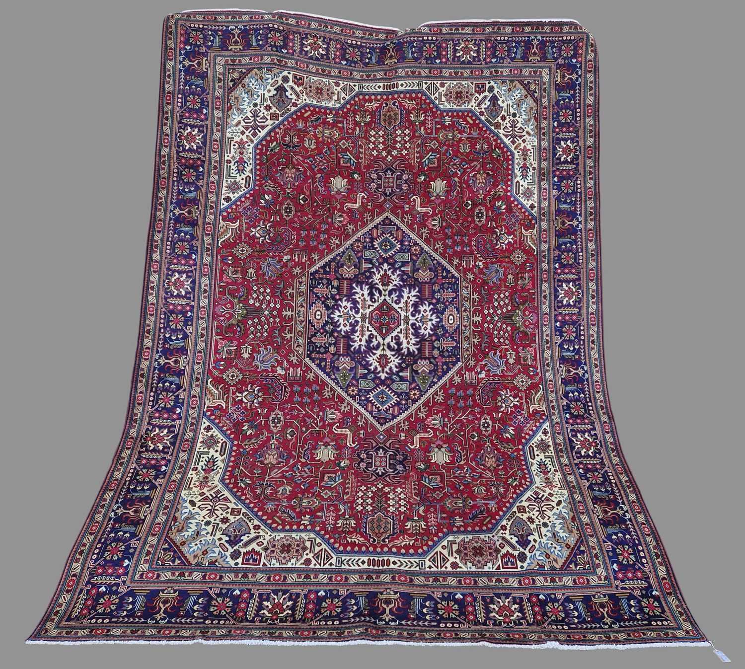 A Persian Tabriz carpet, 20th century, the rectangular madder field centred with a blue ground