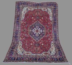 A Persian Tabriz carpet, 20th century, the rectangular madder field centred with a blue ground