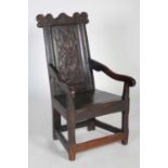 An 18th century oak wainscot elbow chair, the shaped top rail carved with two demi-lune stylised