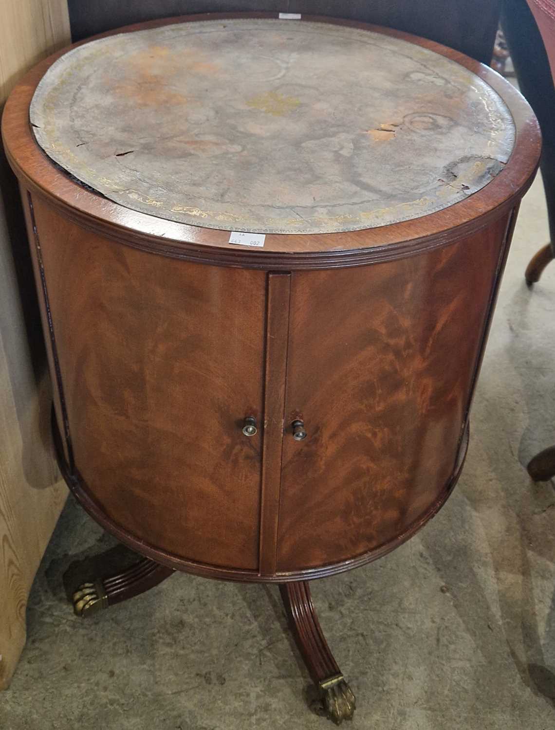 A reproduction mahogany revolving storage cabinet with distressed leather top over two cupboard