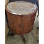 A reproduction mahogany revolving storage cabinet with distressed leather top over two cupboard