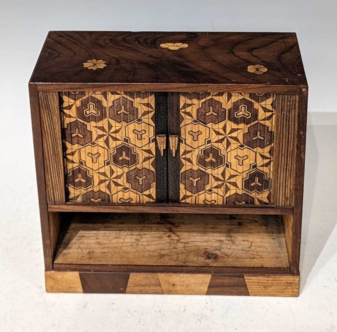 A Meiji period Japanese marquetry table cabinet, the upper section with tambor shutter opening to