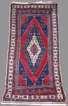 A Persian long rug, 20th century, the rectangular madder ground centred with a large lozenge