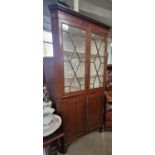 A 19th century mahogany two part corner cupboard, the upper section with astragal glazed doors