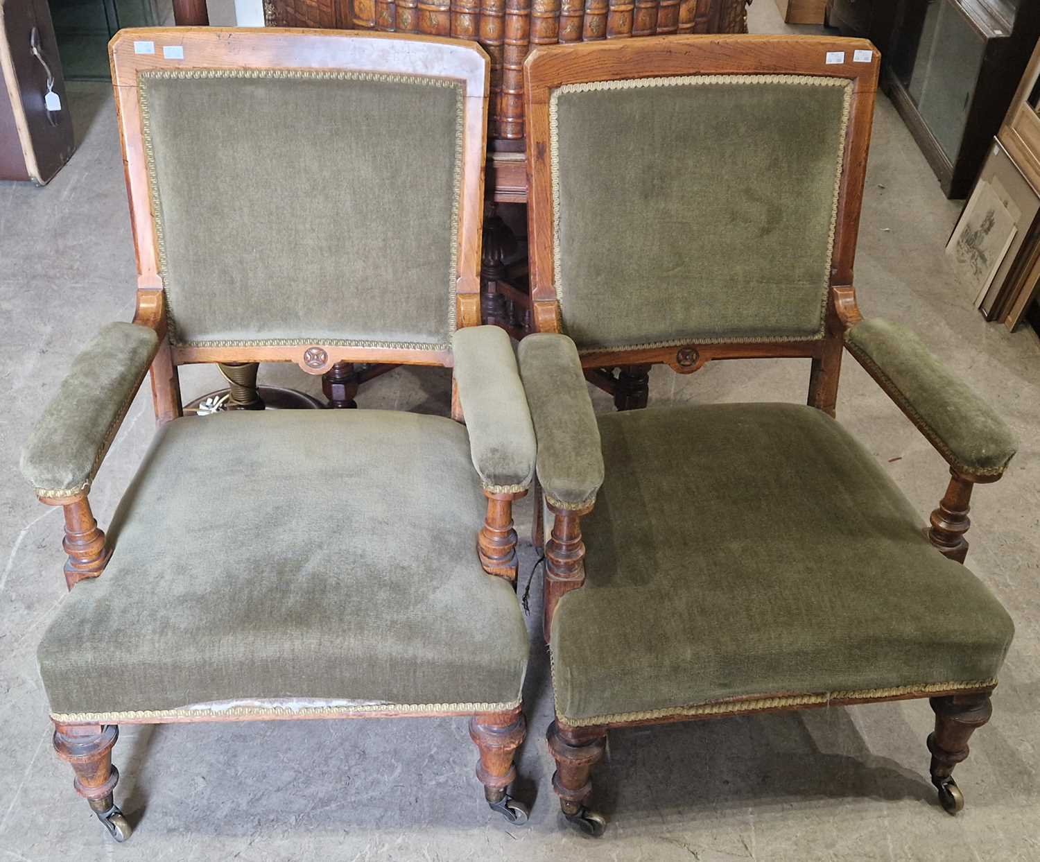 A pair of Victorian oak club armchairs with green velvet upholstered backs, arms and seat, raised on