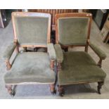 A pair of Victorian oak club armchairs with green velvet upholstered backs, arms and seat, raised on