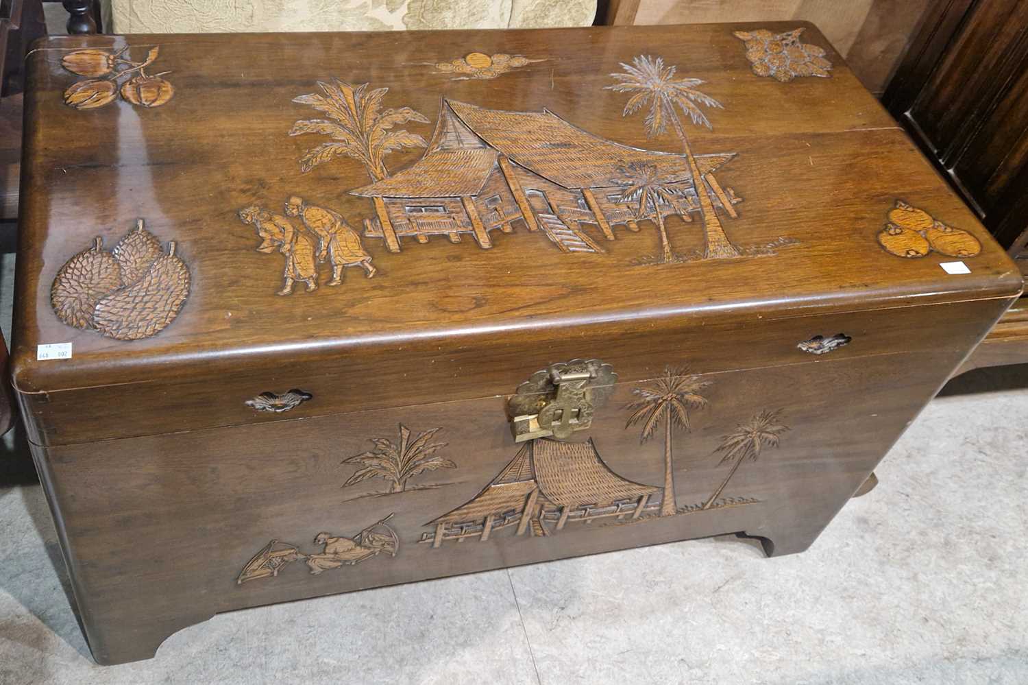 A Chinese carved wood blanket box, decorated in shallow relief with figures, palm trees, pavilions