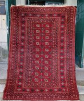 A Persian Tekke rug, the rectangular madder ground centred with two rows of twenty octagonal