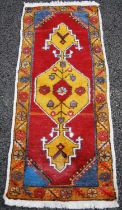 A small Persian rug/ mat, 20th century, the madder ground centred with an ochre-coloured medallion