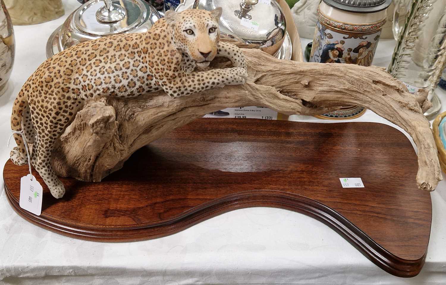 A resin sculpture of a leopard on a branch, mounted to a wooden plinth.