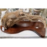 A resin sculpture of a leopard on a branch, mounted to a wooden plinth.