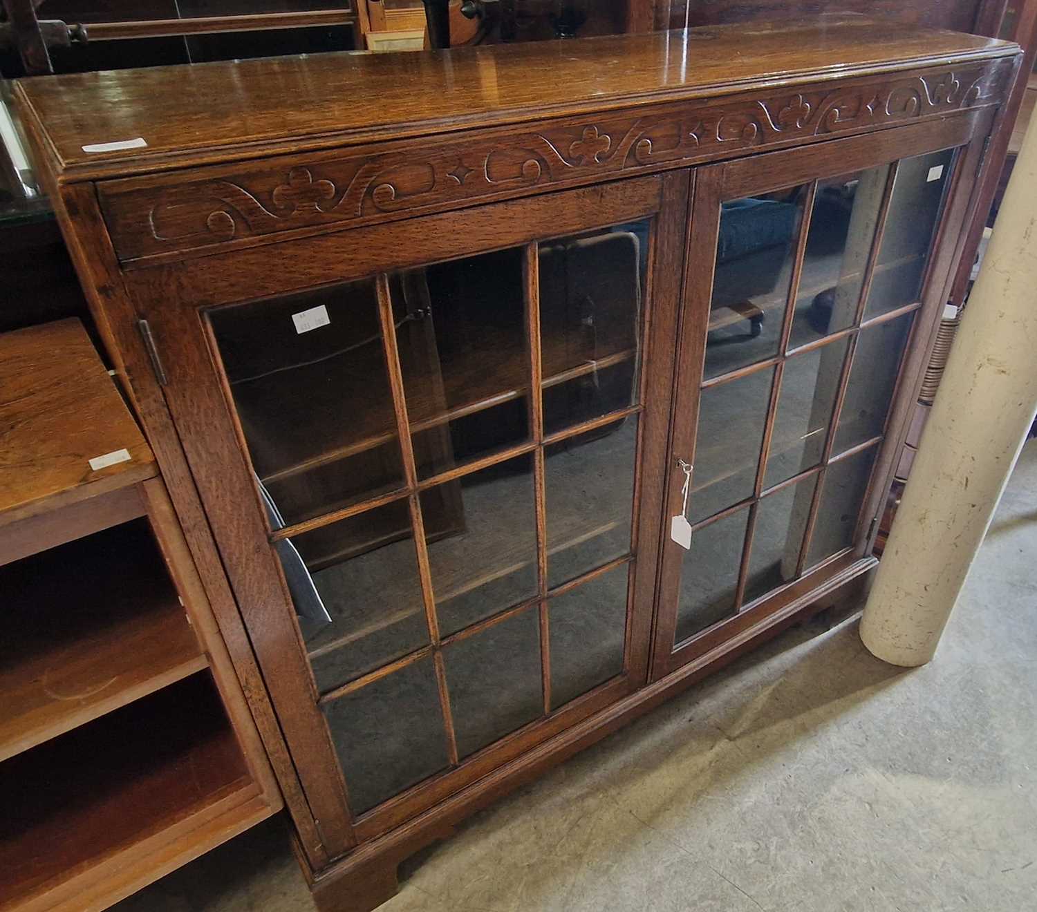 An early 20th century oak bookcase with two glazed doors and adjustable shelves within, 104cm wide.