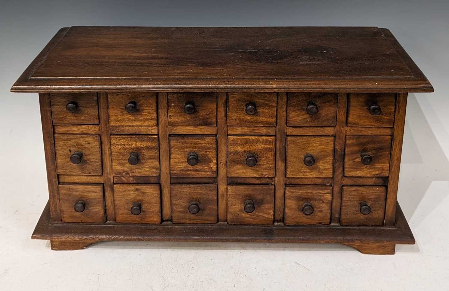 A stained wood table top chest of eighteen small drawers, raised on four bracket feet, 32.5cm