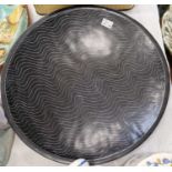 A decorative pottery charger, the black ground with white wavy pin stripe design, the underside