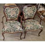 A pair of Edwardian mahogany upholstered armchairs.