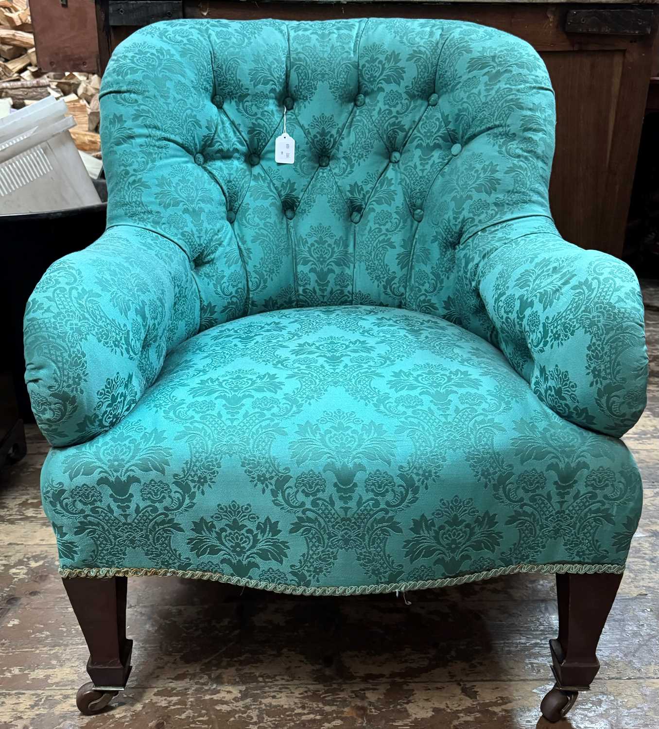 An Edwardian mahogany armchair with blue/green brocade upholstery, raised on tapered square supports