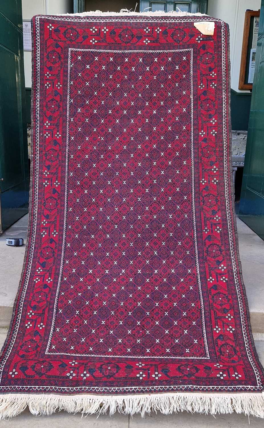 An Iranian madder ground rug, the rectangular field decorated with all over design of octagonal - Image 2 of 4