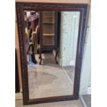An early 20th century rectangular bevelled wall mirror, the frame carved with flowers and foliage,