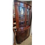 A reproduction mahogany bow front corner cupboard.