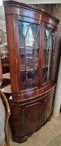 A reproduction mahogany bow front corner cupboard.