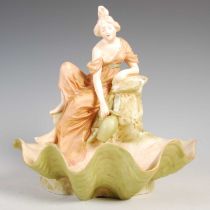 Two Art Nouveau Royal Dux porcelain figures, both modelled with a lady by a shell well, impressed